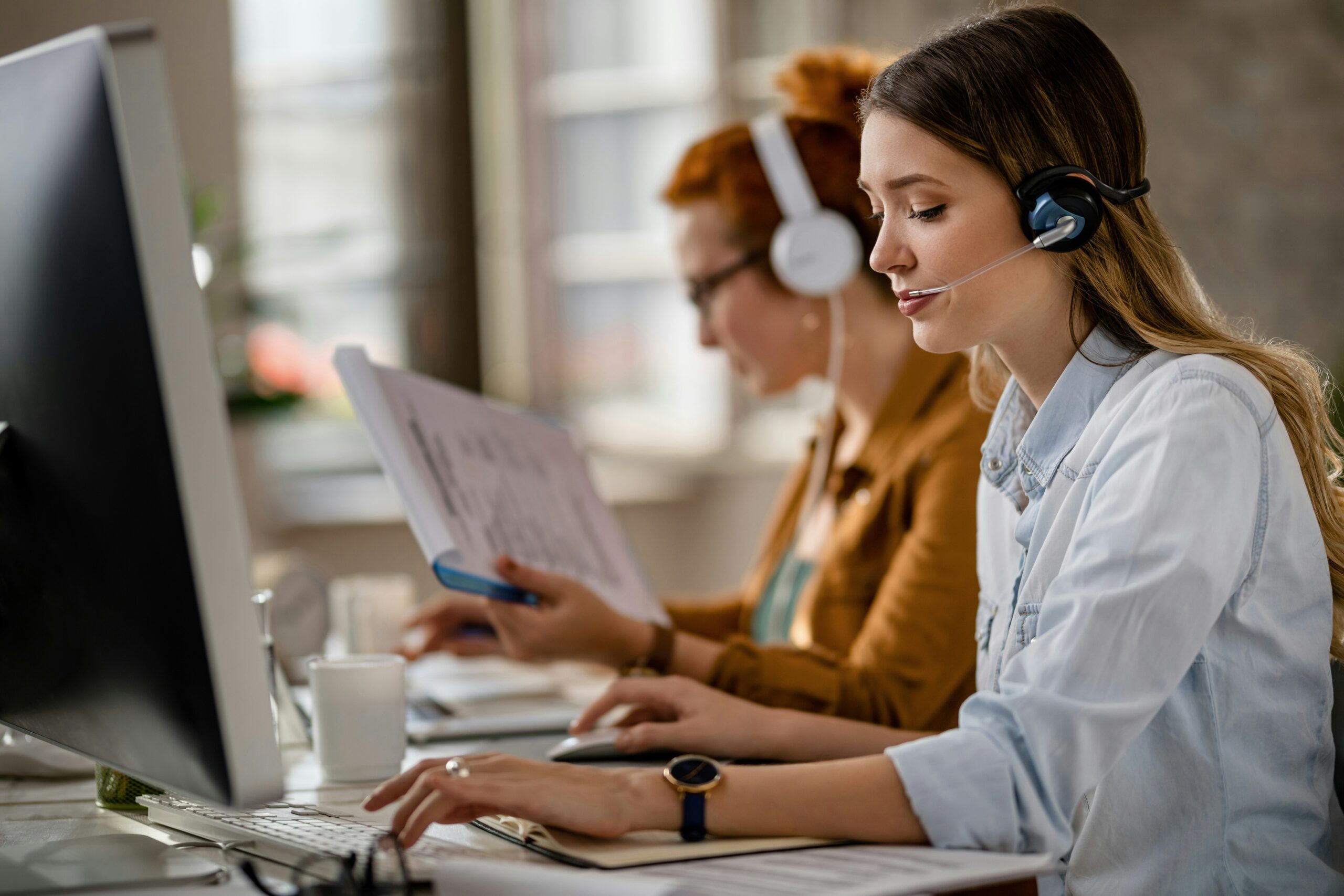Professional women wearing headset working at computer in an office setting, highlighting outsourced HR support